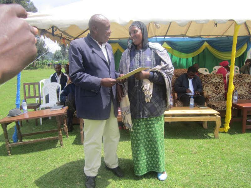 Michel Hategekimana chatting with a resettled resident ,holding certificate of the land disputed for more than 20 years