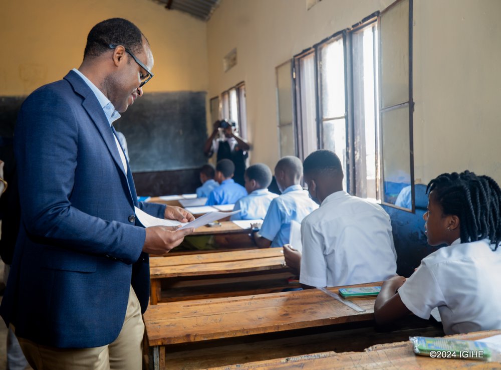 Minister of Education, Gaspard Twagirayezu, hands over examination papers to students at G.S Gisozi I