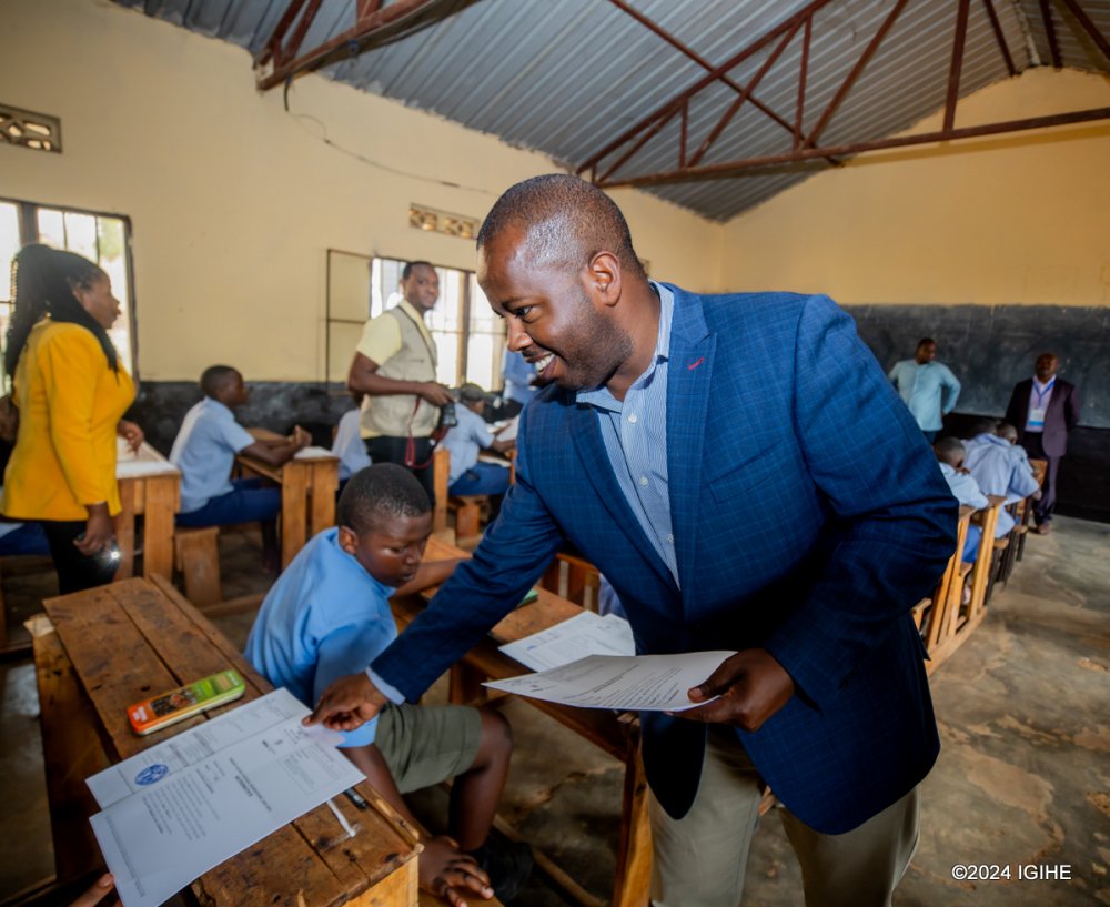 Mayor Dusengiyumva hands over examination paper to students.