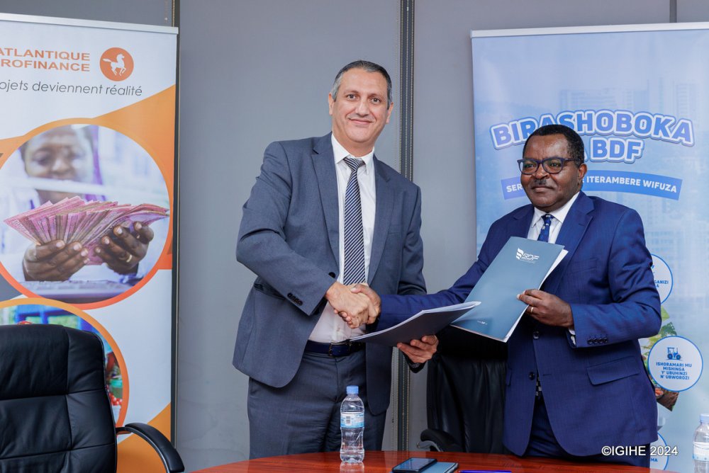The Managing Director of Atlantique Microfinance Plc, Mohamed Aarouch (left) exchanging documents with Munyeshyaka Vincent, the CEO of BDF after signing the agreement.