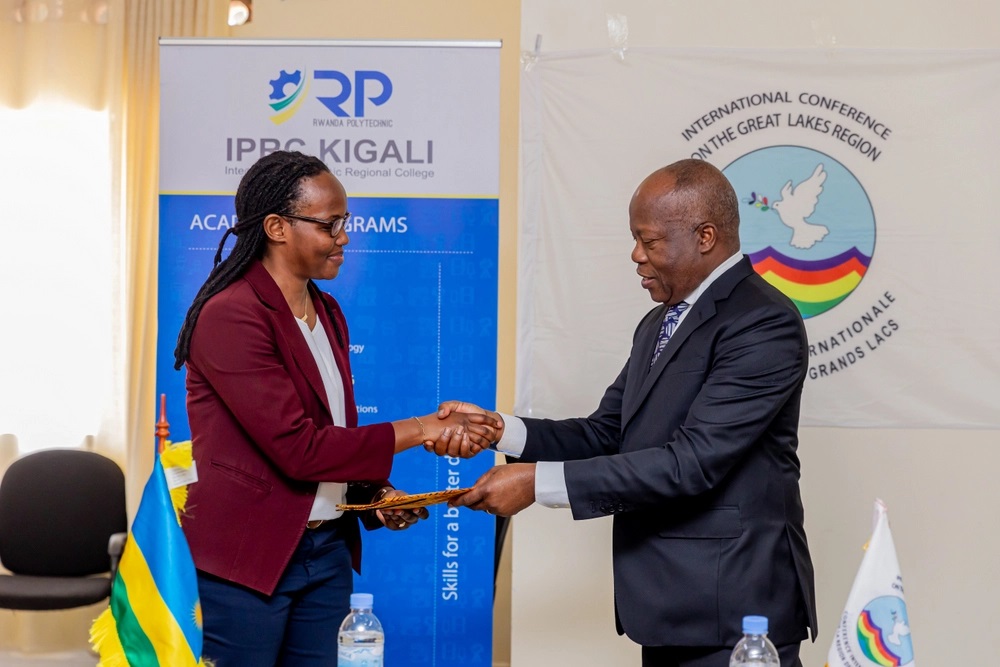Dr Ikuzwe Alice receiving and Amb. Joao Samuel Caholo exchanging an acknowledgment receipt at the event.