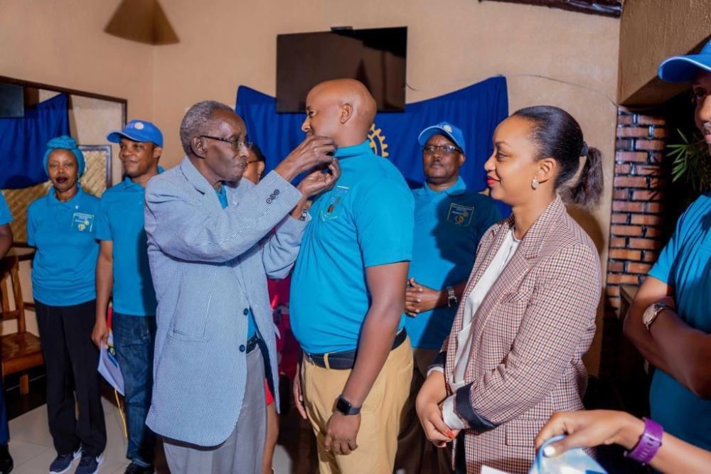 Rtn Arthur Asiimwe, the Director General of RBA closely supported by his wife , gets an official pin of Rotary from President of RCKV Prof Geofrey Rugege.