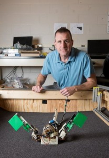 Dan Goldman, associate professor in the Georgia Tech School of Physics, is shown with the "MuddyBot" robot in a trackway used to study how the robot - which was modeled on the mudskipper fish - moved across granular surfaces.