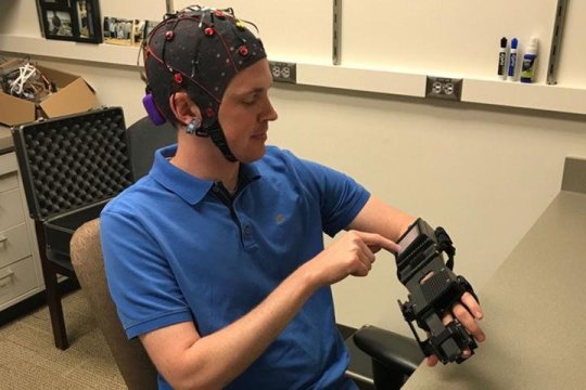 Medical resident Jarod Roland, MD, tries out a device that detects electrical activity in his brain and causes his hand to open and close in response to brain signals. A new study shows that this device can help chronic stroke patients recover some control over their paralyzed limbs.