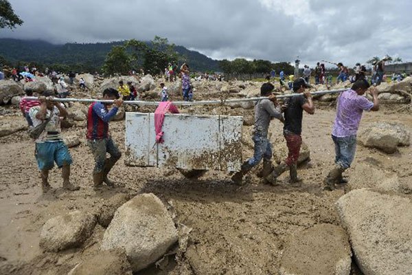 People carry their belongings amidst the rubble left by mudslides following heavy rains in Mocoa, Putumayo department, southern Colombia on April 2, 2017. 