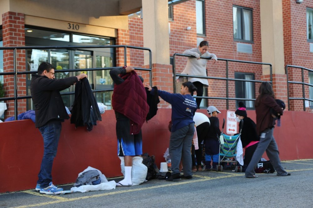 Antonio Ovando (1st L), an asylum seeker who arrived in New York City less than a week ago, picks up clothes dropped off by New Yorkers outside a hotel in Staten Island, New York, the United States, on Oct. 9, 2022.  (Xinhua/Liu Yanan)