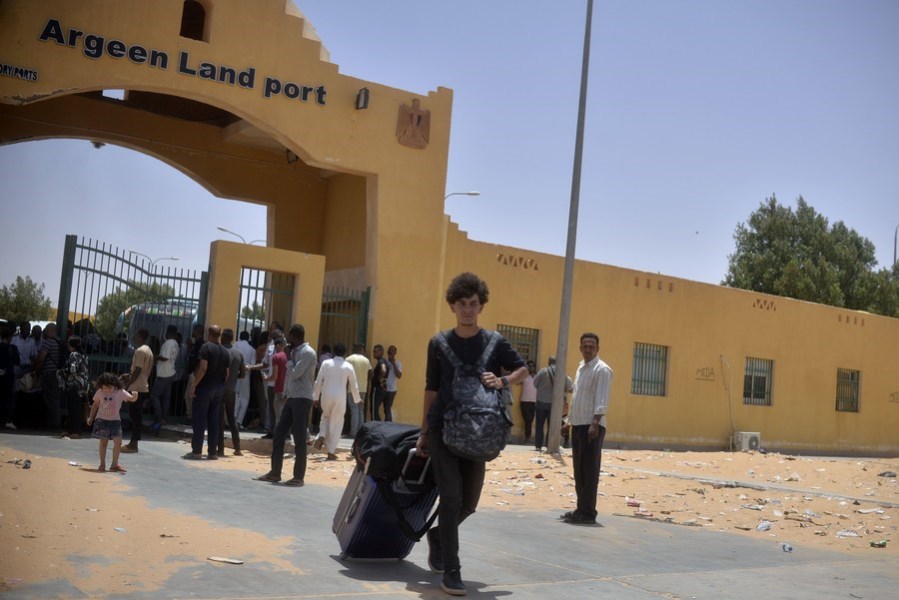 A man carrying luggage is seen after crossing into Egypt through the Argeen land port with Sudan on April 27, 2023. (Photo by Radwan Abu Elmagd/Xinhua)