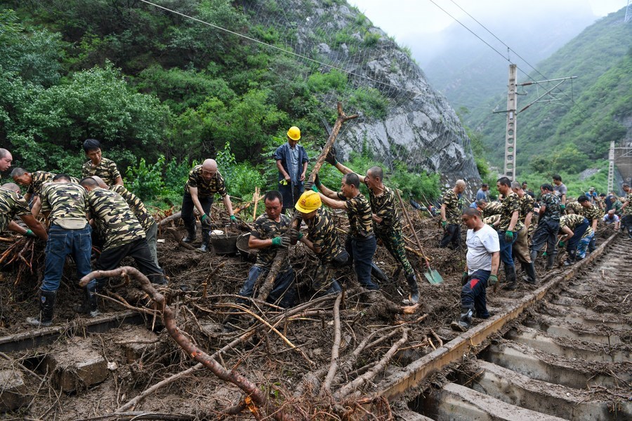 Railway workers remove fallen trees from railway tracks in Shuiyuzui Village in flood-hit Mentougou District, Beijing, Aug. 1, 2023. (Xinhua/Ju Huanzong)