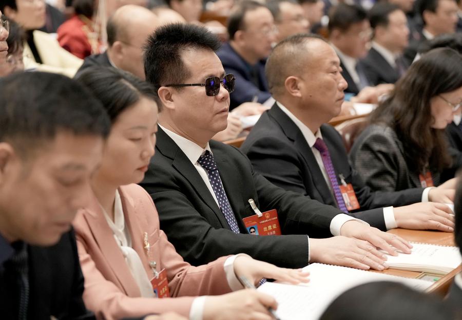 Wang Yongcheng (C) reads the government work report in Braille while attending the opening meeting of the second session of the 14th National People's Congress at the Great Hall of the People in Beijing, capital of China, March 5, 2024. (Xinhua/Wang Yuguo)