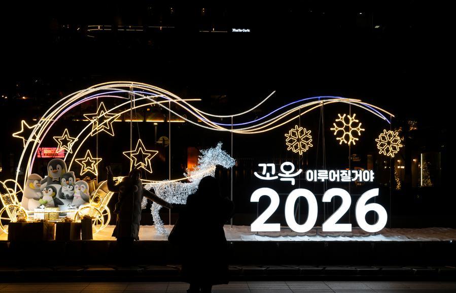 A woman poses for a photo in front of a New Year light display in Seoul, South Korea on December 31, 2025.