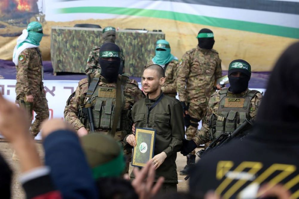 Members of the Al-Qassam Brigades, the armed wing of Hamas, and an Israeli hostage are seen during the handover of three Israeli hostages to the International Committee of the Red Cross, in the al-Nuseirat refugee camp, in central Gaza, on Feb. 22, 2025. (Photo by Xinhua)