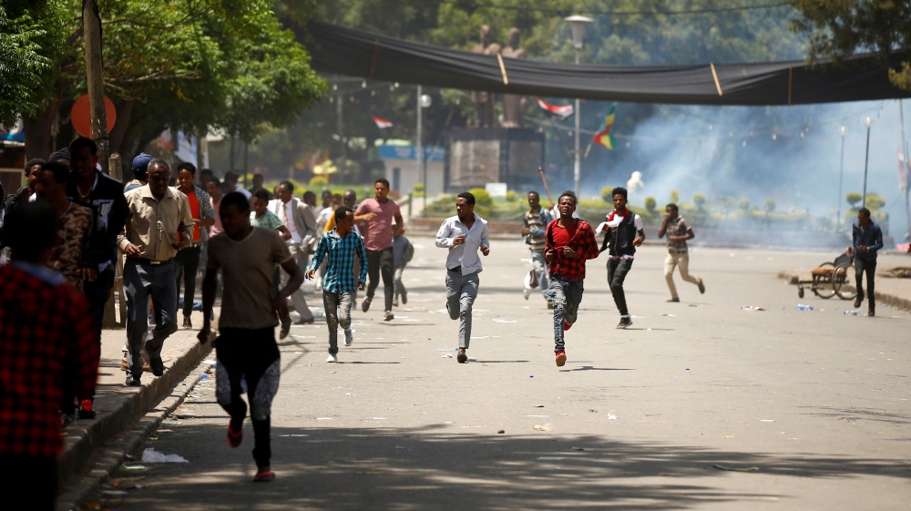 Protesters run from tear gas being fired by police during Irreecha, the religious festival in Bishoftu where at least 52 people died