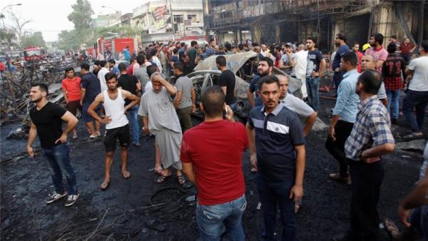 People gather at the site of a suicide car bomb in the Karada shopping area, in Baghdad