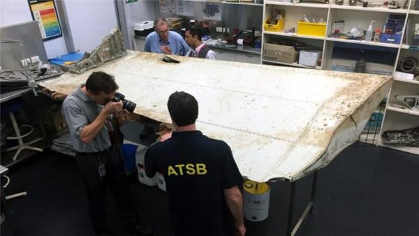 An undated handout picture shows Malaysian and Australian investigators examining a piece of aircraft debris