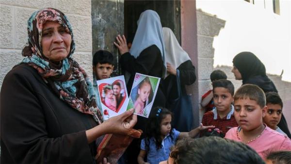 Umm Fadi holds up pictures of her deceased grandchildren