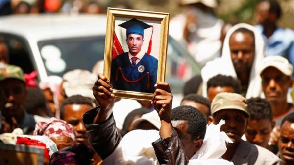 A man at a funeral holds up the portrait of Tesfu Tadese Biru, a construction engineer killed in Bishoftu