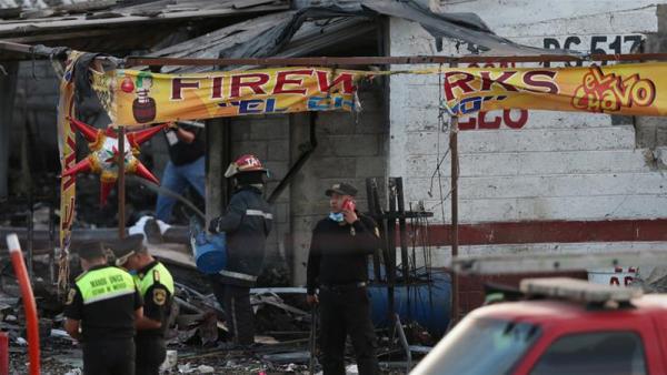 Firefighters stand near a destroyed house after an explosion at the San Pablito fireworks market