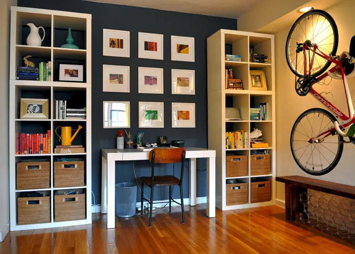 Tall bookshelves, hanging plants, and wall-mounted cabinets draw the eye upward, creating a feeling of spaciousness while also adding storage.