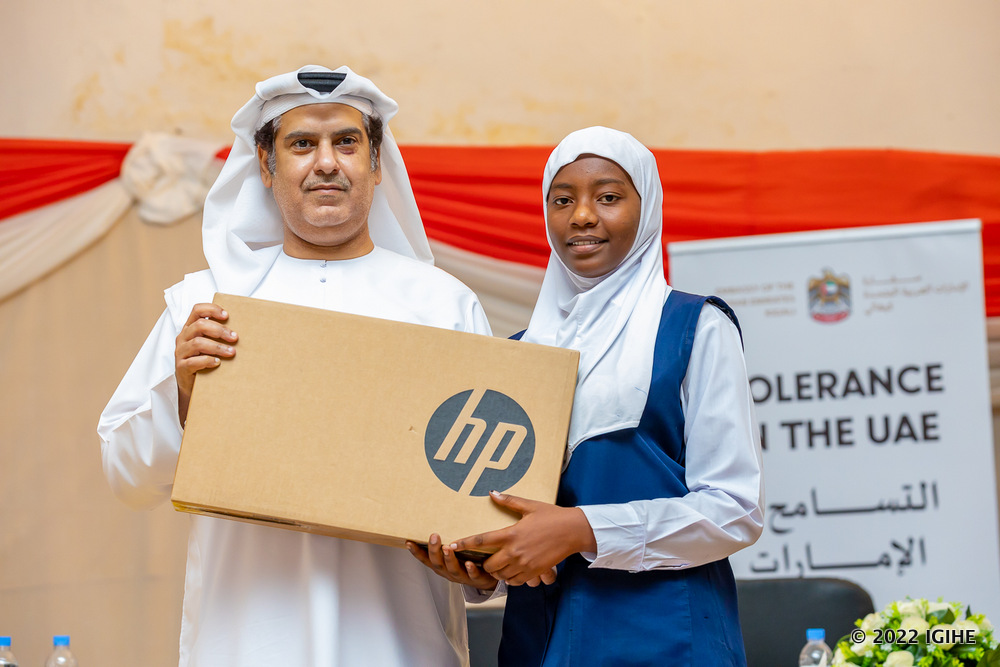 Amb. Alqahtani handing over a laptop to the best performing student. 