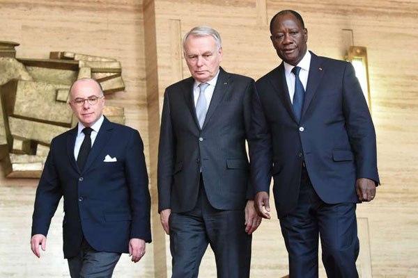 Ivorian president Alassane Ouattara (right) escorts French Foreign Affairs minister Jean-Marc Ayrault (centre) and French Interior minister Bernard Cazeneuve after their meeting, on March 15, 2016 in Abidjan, as part of their visit in a show of solidarity with the country, where three days of mourning have been declared following the weekend assault on a beach resort that killed 18 people.