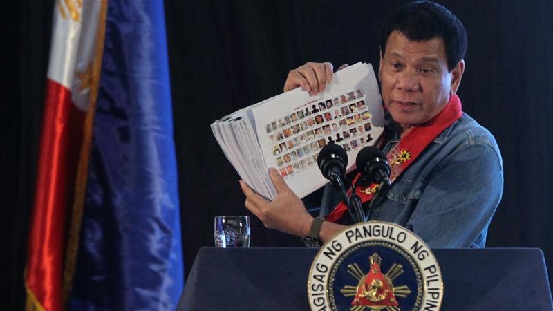 Duterte holds a compilation of pictures of people involved in the drug trade during his speech on Thursday