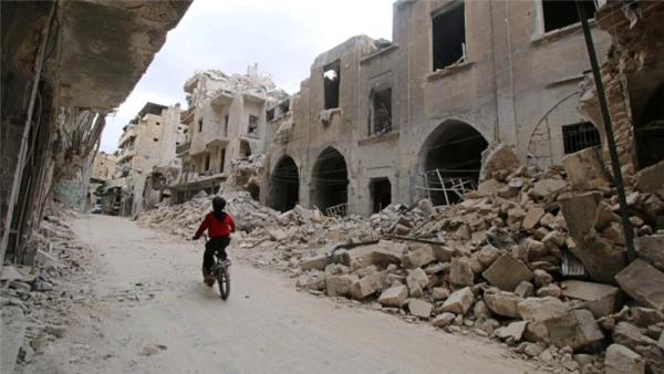 A boy rides a bicycle near damaged buildings in the rebel held area of Old Aleppo, Syria May 5, 2016.