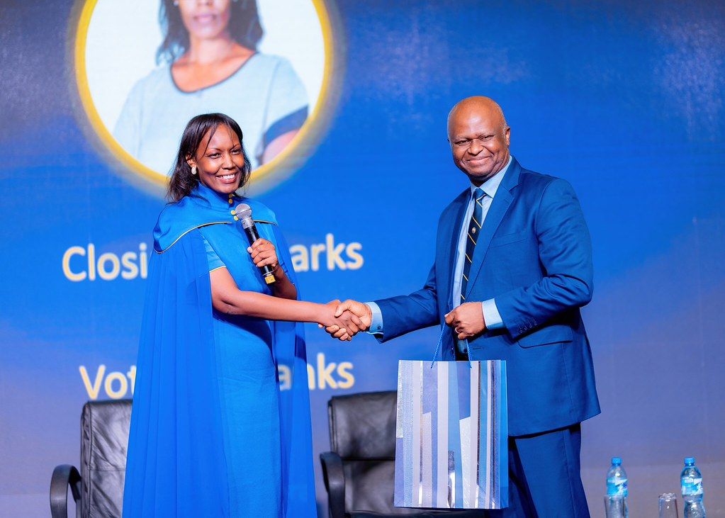 Mireille Karera hands over a copy of her book to Roger Bong Bekondo during the launch ceremony.
