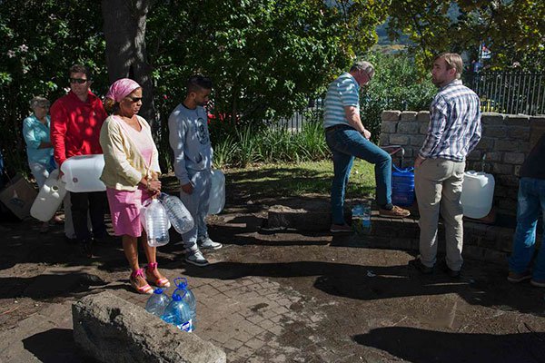 People queue up to collect drinking water from taps that are fed by a spring in Newlands in Cape Town on May 15, 2017.