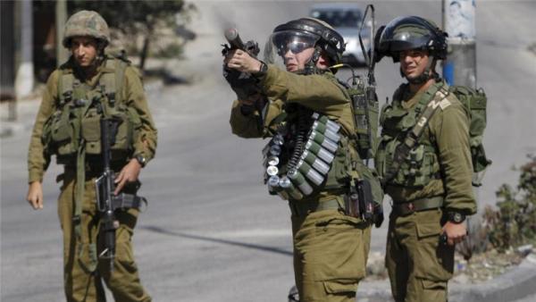An Israeli soldier fires tear gas at Palestinian protesters during recent clashes in Hebron
