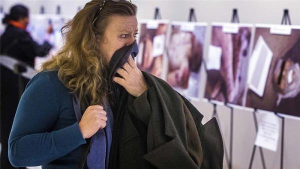 A woman reacts as she looks at a gruesome collection of images of dead bodies taken by Caesar