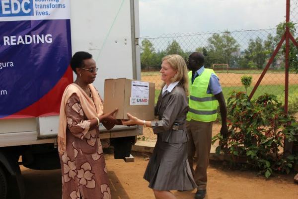 Gasinzigwa receives the teaching and learning materials from Amb. Barks-Ruggles at Ecole Primaire d'Application de Kimihurura