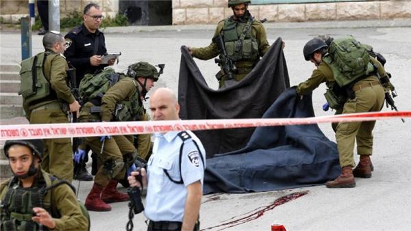 Israeli soldiers cover the body of the Palestinian man shot dead in Hebron on March 24