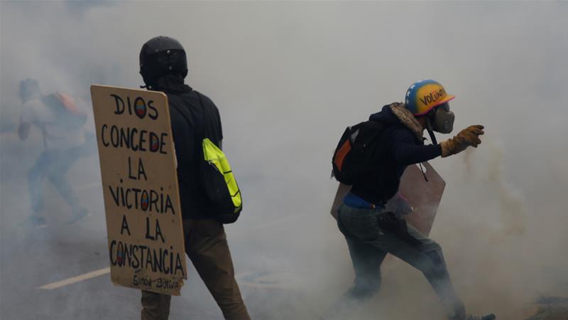 Demonstrators throw tear gas canisters back as they clash with security forces on Monday