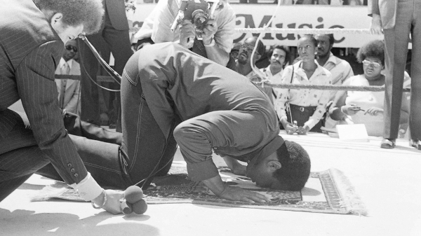 Muhammad Ali prays at a press conference before his fight against Ken Norton