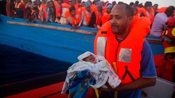 A man carries his five-day-old son onto a rescue vessel