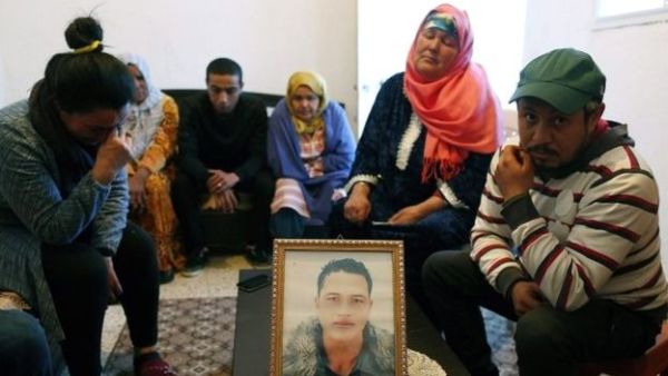 The family of Anis Amri sit around a portrait of him in their home in Oueslatia, Tunisia