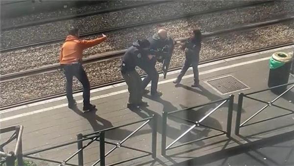 An image showing police as they coax a young girl away from a suspect laying on the ground at a tram stop in Brussels on Friday