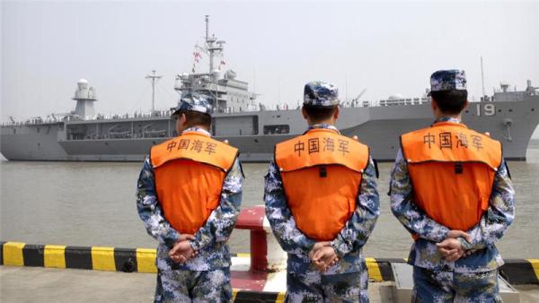 Soldiers from the Chinese People's Liberation Army Navy watch as the USS Blue Ridge arrives at a port in Shanghai