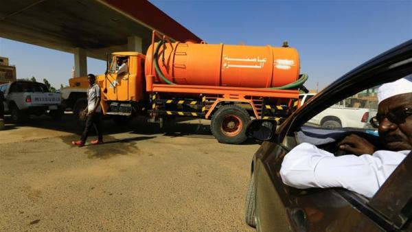 People gather to get fuel at a petrol station in Khartoum amid subsidy cuts