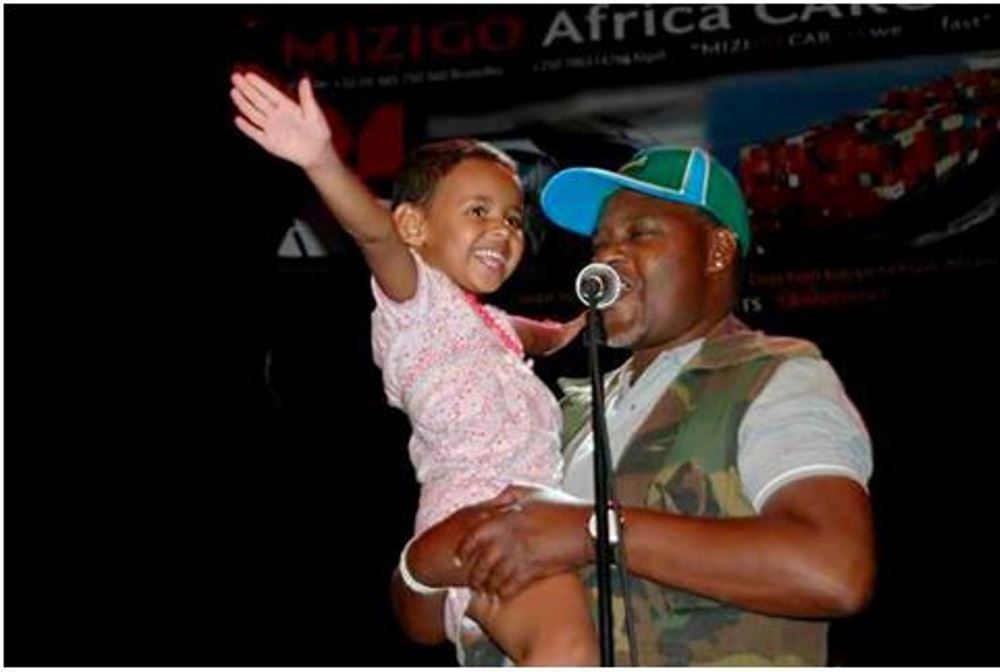 Marie-Emilie, aged 4, on stage in the arms of Marechal De Gaulle Ufiteyezu. 