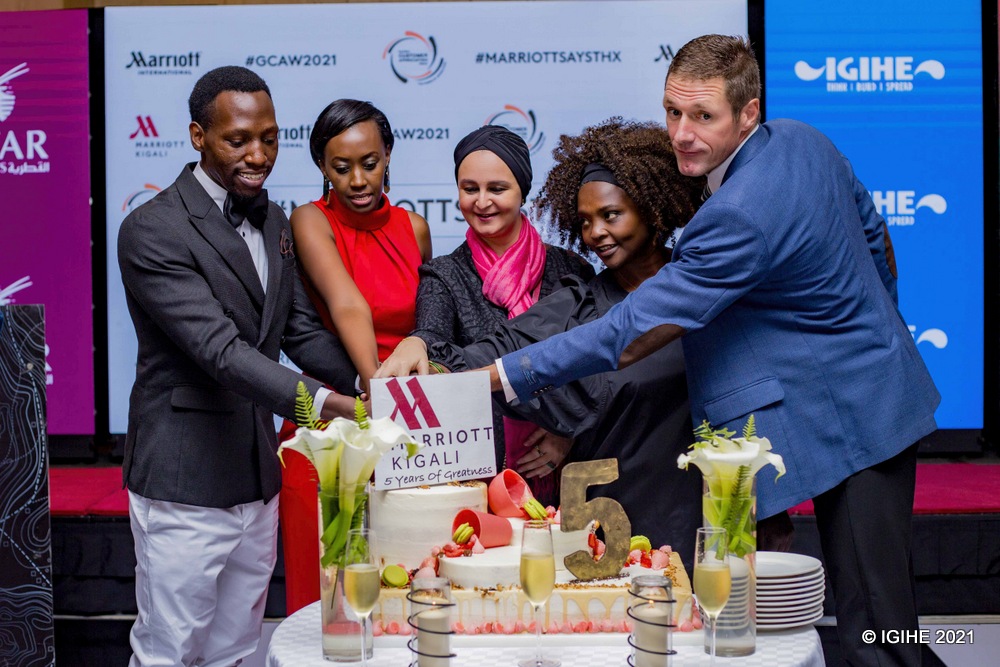Customers and the hotel's team cutting a cake in celebration of five-year anniversary. 