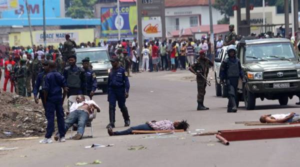 The bodies of people killed during election protests lie in the street, as Congolese troops stand near by in Kinshasa, Democratic Republic of Congo, Monday, Sept. 19, 2016.