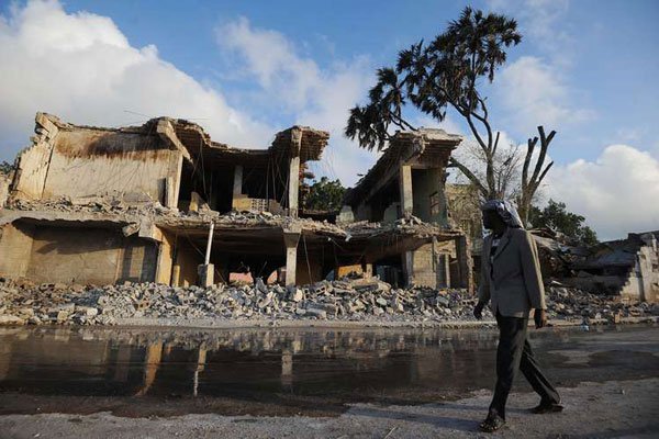 A Somali national walks near a destroyed building after the attack on SYL hotel on February 27, 2016 in Mogadishu, Somalia.