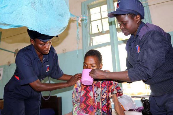 Security guards help Millicent Awino to drink porridge at her hospital bed at Kisumu County Hospital on December 6, 2016.