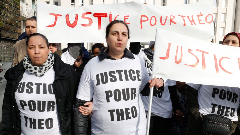 Women hold signs reading "Justice for Theo" during a protest on February 6