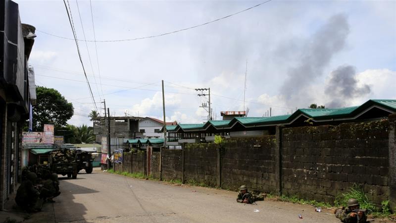 Black smoke is seen in the air while government troops position themselves during an assault against the fighters