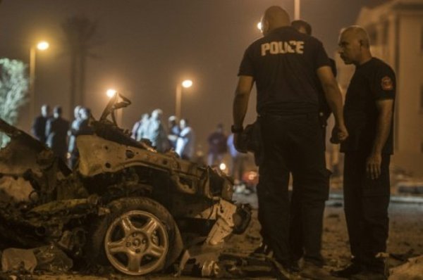 Egyptian policemen inspect the wreckage of a car bomb that exploded in a Cairo suburb after Egypt's deputy prosecutor general drove by wounding a passerby