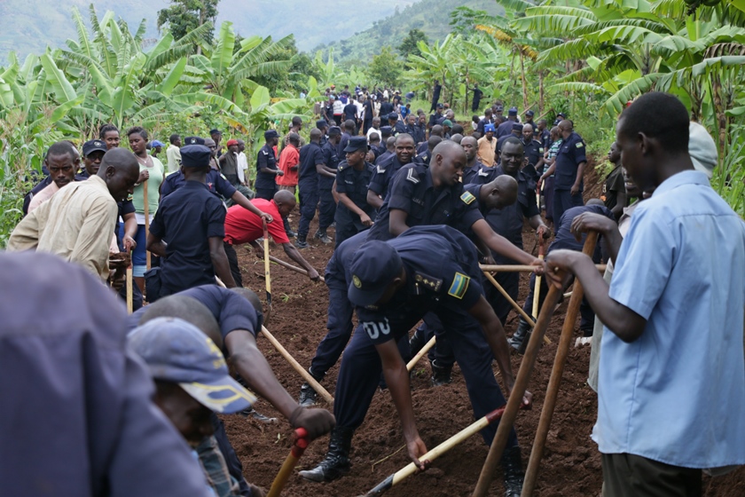 Police joining citizens in community work to create a road.