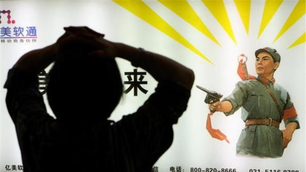 A subway passenger stretches as she waits in front of a poster showing a Cultural Revolution-era image