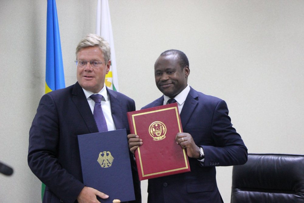 Ambassador of German to Rwanda Dr. Peter Woeste and Minister Dr. Uzziel Ndagijimana exchange documents after signing the grant agreement.